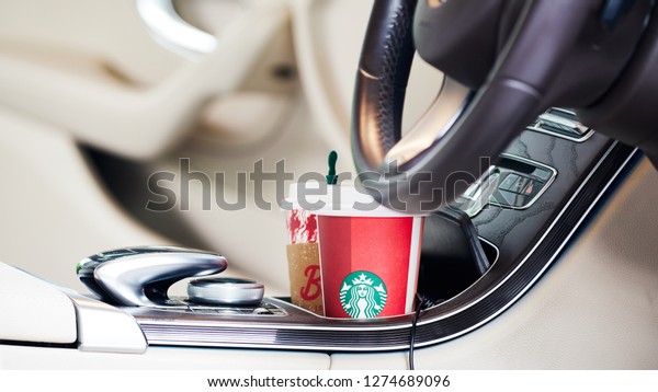 BANGKOK, THAILAND - December 23, 2018: Close up of\
Red coffee cup with Starbucks logo on cup holders in between front\
car seats