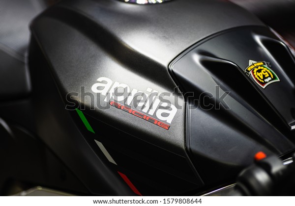 Bangkok, Thailand -\
Decemeber 5, 2019 : Aprilia racing  logo on the body of black\
sports motorbike at a car show. Aprilia is an Italian motorcycle\
company, owned by\
Piaggio.