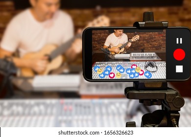 Bangkok, Thailand - Feb 26th 2020 : Asian music vlogger streaming a live video while playing acoustic guitar in home studio
