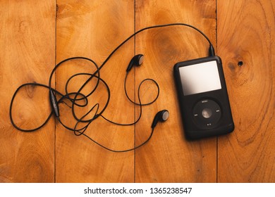 BANGKOK, THAILAND - FEB 3: Close up on iPod classic 120 GB in black case with headphone on a wooden table background on February 3, 2017 in Bangkok, Thailand. 