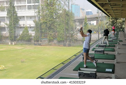 Bangkok, Thailand - February 1, 2011: People practise their swing at a city centre golf driving range.