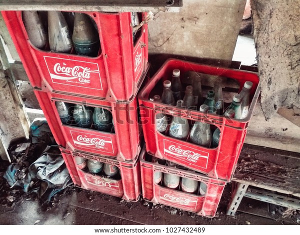 BANGKOK, THAILAND - FEBRUARY 18, 2018:  Mixed brand of\
popular Soft drink/sparkling water soda; Coca-Cola, Fanta, Sprite\
empty glass bottles in red plastic containers in old house storage.\
