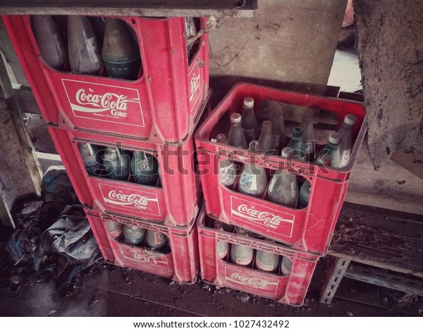 BANGKOK, THAILAND - FEBRUARY 18, 2018:  Mixed brand of\
popular Soft drink/sparkling water soda; Coca-Cola, Fanta, Sprite\
empty glass bottles in red plastic containers in old house storage.\
