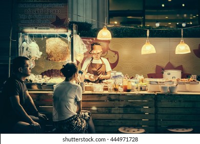 BANGKOK, THAILAND - FEBRUARY 26, 2016: People Are Buying Food At Night Street Food Market In Bangkok, Thailand. Toned Picture