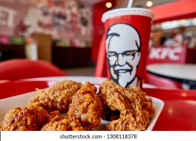 BANGKOK, THAILAND- FEBRUARY 6, 2019 : Crispy fried chicken & cup of drink served in retail background of KFC restaurant. KFC is popular fast food chain known as Kentucky Fried Chicken. Selective focus