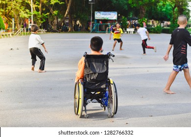 Bangkok, Thailand - JAN 01, 2019: Disabled boy sitting on a wheelchair looking at the normal life of people in the park.