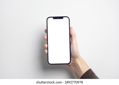 Bangkok, Thailand - Jan 13, 2021: Close Up Hand Holding Black Smartphone IPhone 12 Pro Max With White Screen. Isolated On White Background. Mobile Phone Frameless Design Concept.