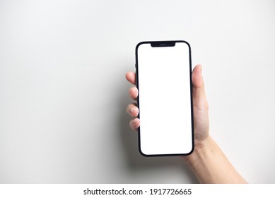 Bangkok, Thailand - Jan 13, 2021: Close Up Hand Holding Black Smartphone IPhone 12 Pro Max With White Screen. Isolated On White Background. Mobile Phone Frameless Design Concept.