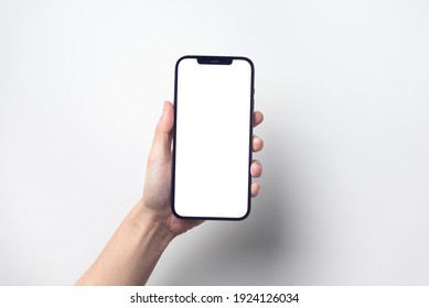 Bangkok, Thailand - Jan 13, 2021: Close up hand holding black smartphone iPhone 12 Pro Max with white screen. Isolated on white background. Mobile phone frameless design concept.