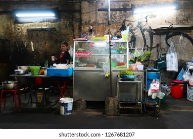 Bangkok, Thailand - January 23, 2018: A Woman Preparing Food At A Street Food Stall In A Dark Alley In Bangkok, Thailand                               