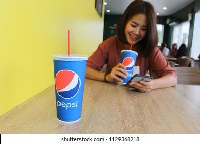 Bangkok, Thailand : July 07,2018: Drink Produced By PepsiCo On The Wooden Table And Young Woman Drink Pepsi In Restaurant