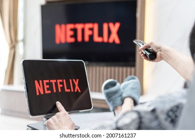 Bangkok, Thailand - July 13, 2021: Netflix app logo on ipad and smart TV television screen sharing in home living room for movie watching during new normal lifestyle