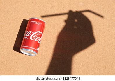 BANGKOK, THAILAND - July 2, 2018: 
Black Silhouette On A White Sand Hand Holding Plastic Straws With Coke Can. Coca Cola Is American Beverage Company Was Founded In 1886 By Pharmacist.