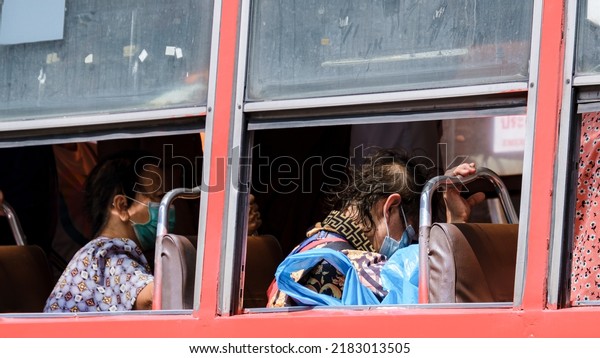 Bangkok Thailand July 2022 people with mask in a red\
bus public transport during covid 19 pandemic. people using public\
transport with face\
mask