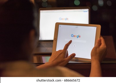 BANGKOK, THAILAND - July 29, 2017: Freelancer Female Using Ipad Mini With Macbook Pro With Google Search Engine On Web Page Working At Night  From Home.International Data Privacy Day .