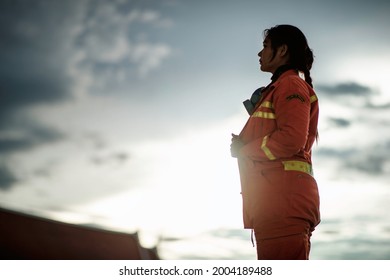 BANGKOK, THAILAND – JULY 7: An Asian Female Firefighter Dressed In Orange Is Standing Looking At The Sky In The Evening Hours On July 7, 2021 In Bangkok, Thailand.