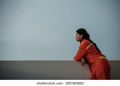 BANGKOK, THAILAND – JULY 7: An Asian Female Firefighter In An Orange Dress Is Resting On The Balcony On July 7, 2021 In Bangkok, Thailand.