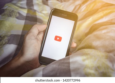 Bangkok, Thailand - June 10, 2019 : Hand Holding IPhone 7 On Bed With YouTube Application On The Screen.