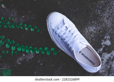 Bangkok, Thailand - June 16, 2022 : White sneaker,Converse Jack Purcell on cement background with tree .Famous vintage style sneaker.Concept is Life is a journey,I love adventure,Endless journey.