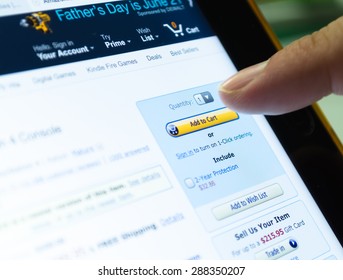 Bangkok, Thailand - June 17, 2015  : Unidentified human finger touch on screen of tablet device on 'Add to Cart' button in Amazon ,largest famous online shopping website, to buy some product