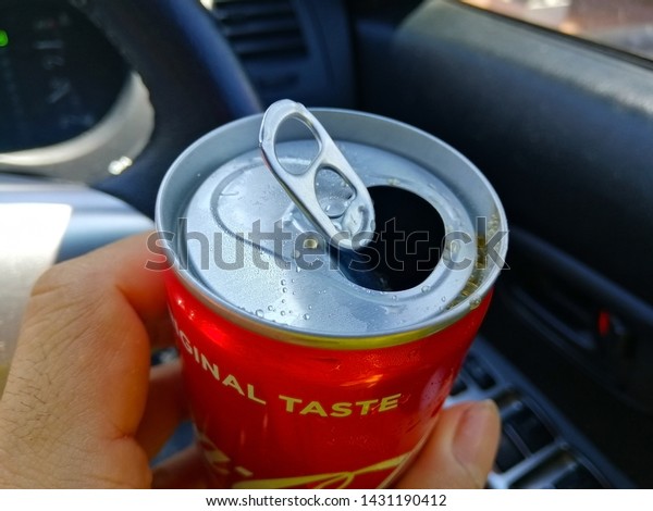 Bangkok, Thailand\
- June 21, 2019: Closeup of hand man holding Coca Cola can in the\
car. Holding cans of soft\
drinks