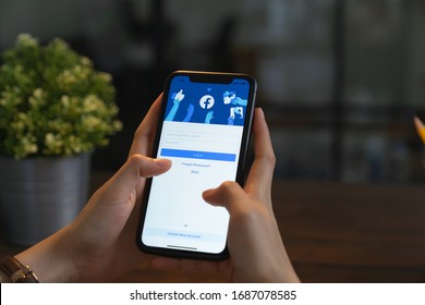 BANGKOK, THAILAND - Mar 30, 2020 : Hand Is Holding Smartphone And The Facebook Screen On Apple IPhone, Social Media Are Using For Information Sharing And Networking.