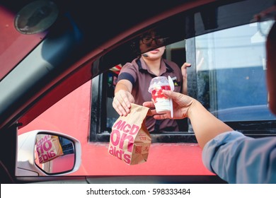 Bangkok, Thailand - Mar 4, 2017: Unidentified customer receiving hamburger and ice cream after order and buy it from McDonald's drive thru service, McDonald's is an American fast food restaurant chain