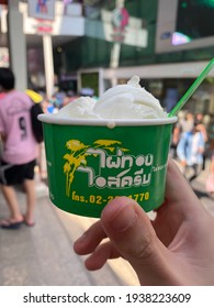 BANGKOK, THAILAND- MARCH 15, 2021: Hand holding coconut ice cream cup of 'PAITHONG ICE CREAM' local Thai dessert food cart