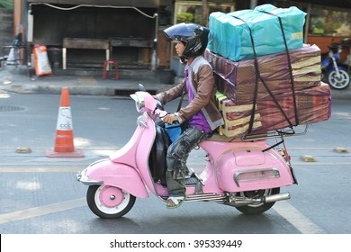 Bangkok, Thailand - March 19, 2013: A motorcyclist rides an overloaded Vespa on a city street. The use of motorbikes by couriers to transport goods and make deliveries is common in the Thai capital.