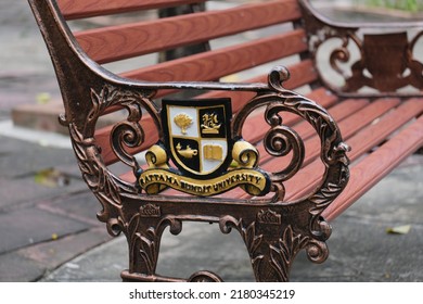 Bangkok, Thailand - March 22 2022: A Retro-style Bench At The Campus Of Rattana Bundit University, With A Cast-iron University's Coat Of Arms