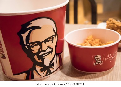 BANGKOK, THAILAND - MARCH 26, 2018: KFC,  Kentucky Fried Chicken Food: Chicken Nuggets Bucket, French Fries and Cheese Sauce. KFC is a Worldwide Famous American Fast Food Restaurant. blurred