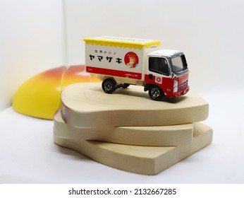 Bangkok, Thailand - March 3, 2022: A model of bread truck of "Yamazaki" bakery brand on a stack of wooden toy bread. Toy truck from Japanese "Tomica" brand.