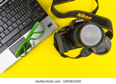 Bangkok, Thailand - March, 31, 2020 : Green Frame Glasses, Notebook Computer And Dslr Nikon D5300 Isolated On Yellow Background.