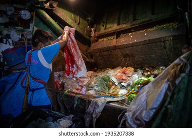 Bangkok, Thailand - March 4th 2020: Man Unloading Rubbish Onto The Garbage Truck At Night At The 'Khlong Toei' Wet Market; The City's Largest Wet Market.