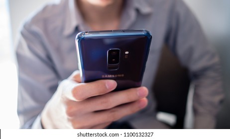 Bangkok, Thailand - May 19th 2018 : A man in gray shirt use blue Samsung galaxy S9 plus, Andriod mobile phone.