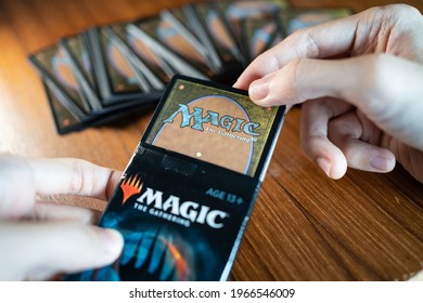 Bangkok, Thailand - May 2, 2021 : A man opening Magic The Gathering card booster pack.