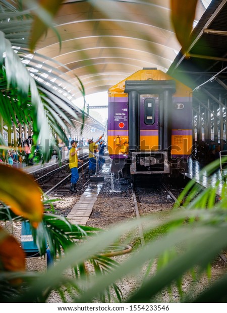 Bangkok, Thailand - May 25,\
2019: An employee washes a railway passenger car at Hua Lamphong, A\
group of workers washes train cars at the Bangkok main train\
station