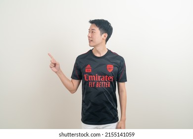 Bangkok, THAILAND - Nov 27, 2021 : Young Asian man wearing Arsenal shirt with white background. Arsenal football club is a famous team in London city.