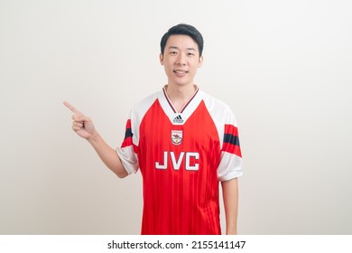 Bangkok, THAILAND - Nov 27, 2021 : Young Asian man wearing Arsenal shirt with white background. Arsenal football club is a famous team in London city.