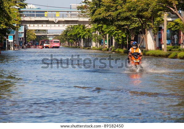 BANGKOK,\
THAILAND - NOVEMBER 12 : Two men on a motorbike navigating through\
the flood after the heaviest monsoon rain in 20 years in the\
capital on November 12,2011 Bangkok,\
Thailand.