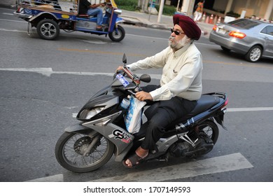 Bangkok, Thailand - November 15, 2012: A Man Wearing A Sikh Turban Rides A Motorbike Along A City Centre Street. People Who Wear Religious Headwear Are Except From Motorcycle Helmet Laws In Thailand.