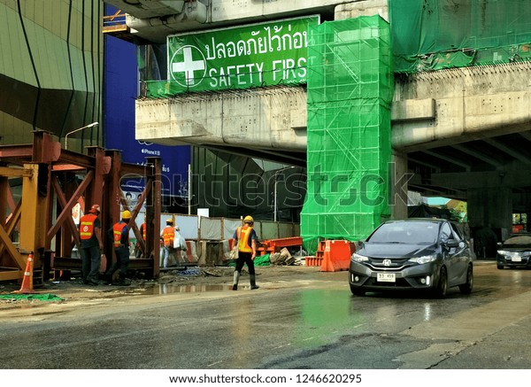 Bangkok,\
Thailand - November 18,2018 : Construction workers group are\
walking to work at flyover construction site on the street in\
downtown with green warning safety sign\

