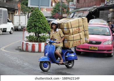 Bangkok, Thailand - November 22, 2017: A motorcyclist rides an overloaded Vespa on a city street. The use of motorbikes by couriers to transport goods and make deliveries is common in the Thai capital