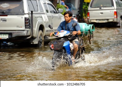 Bangkok, Thailand - November 5, 2011 : A delivery man drives a motorcycle on a flooded street after torrential rain on November 5, 2011 Bangkok, Thailand