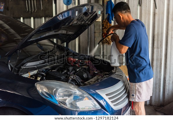 Bangkok, Thailand - October 10, 2018 : Unidentified\
car mechanic or serviceman cleaning the car engine after checking a\
car engine for fix and repair problem at car garage or repair\
shop