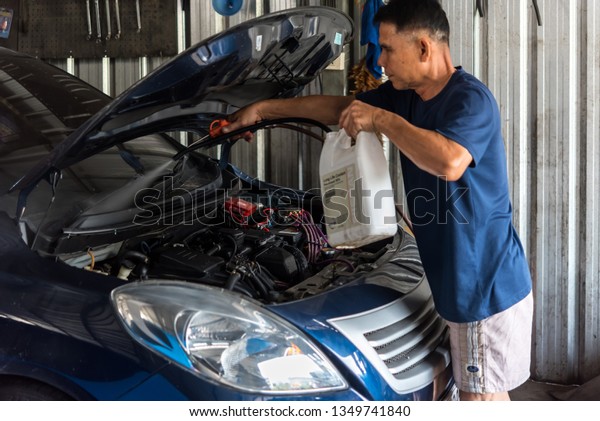 Bangkok, Thailand - October 10, 2018 : Unidentified\
car mechanic or serviceman cleaning the car engine after checking a\
car engine for fix and repair problem at car garage or repair\
shop