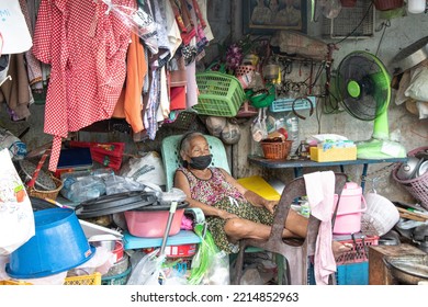 Bangkok  Thailand - October 17 2022: An Elderly Woman Appears To Camouflage Into Rails Of Clothes And Junk Piled Up Outside Her Home