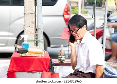 Bangkok  Thailand - October 17 2022: A Fortune Teller Speaks On His Mobile Phone While Waiting For Customers