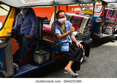 BANGKOK, THAILAND - OCTOBER 2021: happy smiling asian thai tuk-tuk driver showing thumb up and waiting for passengers, wearing face mask due to COVID-19 coronavirus pandemic in Yaowarat Chinatown  