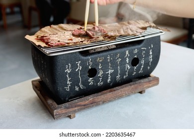 Bangkok ,Thailand - Sep 18,2022 : Wagyu Beef Grill.Japanese Cuisine, Grilled Beef On Wooden Tabletable.Japanese Beef Steak On Grill Plate.Hand Using Chopsticks To Pick Up Wagyu, Grilled Wagyu.